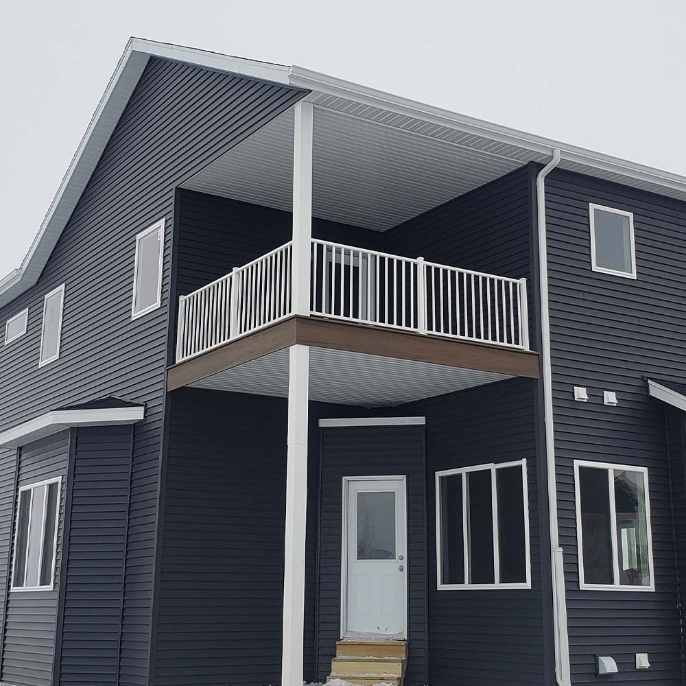 Modern, two-story house with dark siding, white trim, and a small covered balcony. The mood is contemporary and clean, with a minimalist design.