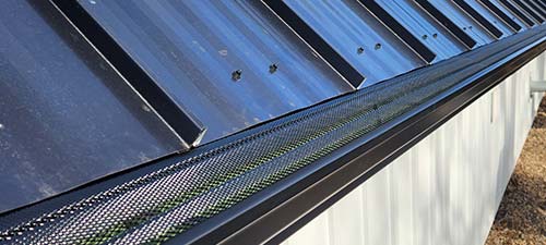 Black metal roof with a new gutter guard installed.